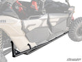 Can-Am Maverick X3 MAX Tree Kickers are shown mounted below the door of a beige off-road vehicle with rugged tires and visible suspension. The background fades to highlight the tree kickers, with the SuperATV logo in the corner.
