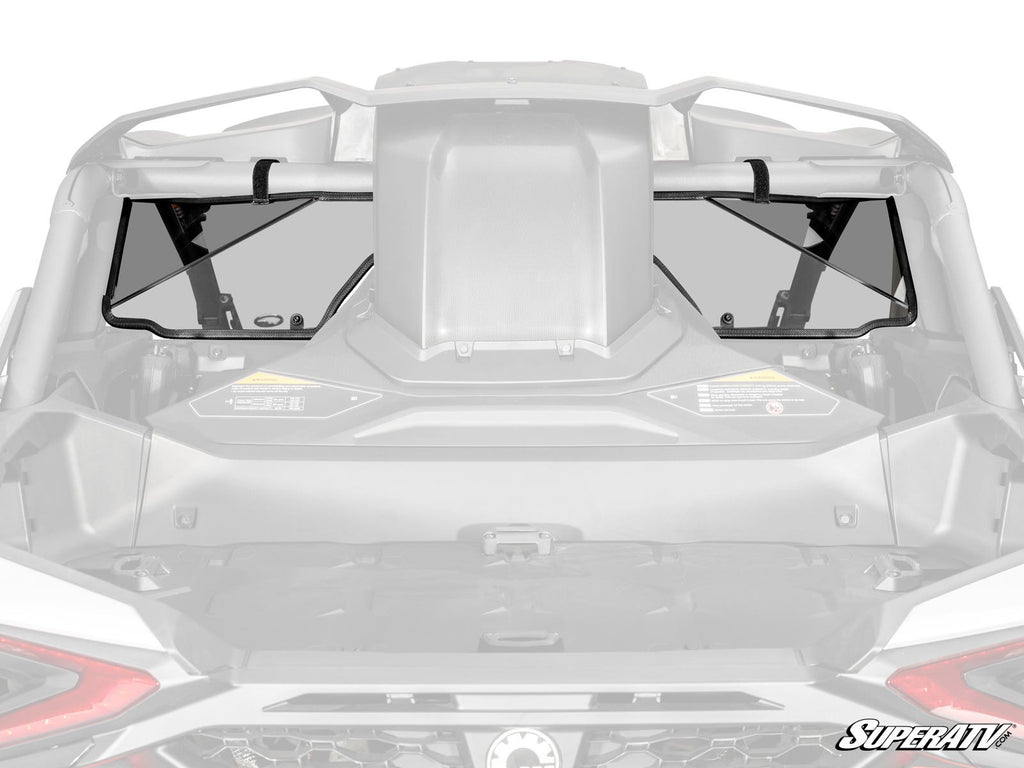 Close-up rear view of a Can-Am Maverick R with the SuperATV Rear Windshield installed. The clear, two-panel windshield is secured to the roll cage with black mounting straps and features the SuperATV logo in the bottom right corner.