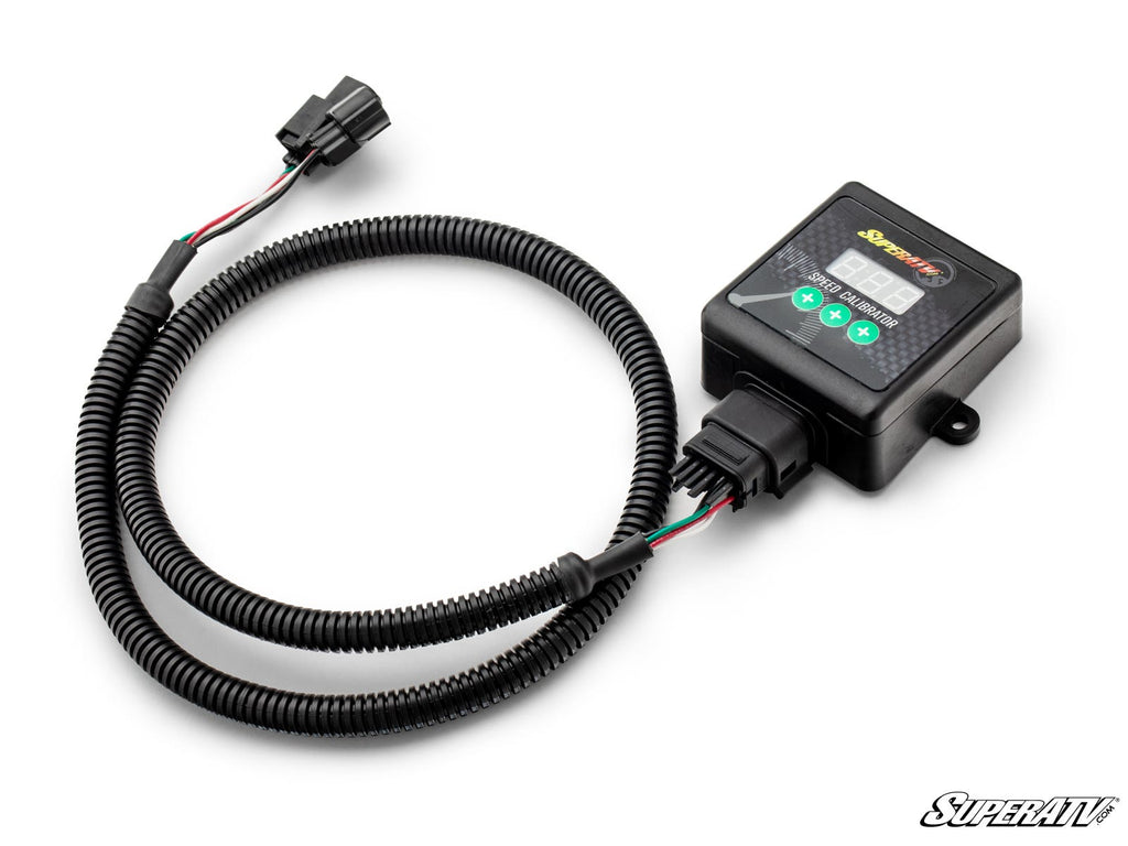 A black SuperATV Can-Am SpeedDoctor Speedometer Correction Kit with a digital display and four buttons, attached to a long coiled wire with a plastic connector, is shown against a plain white background.