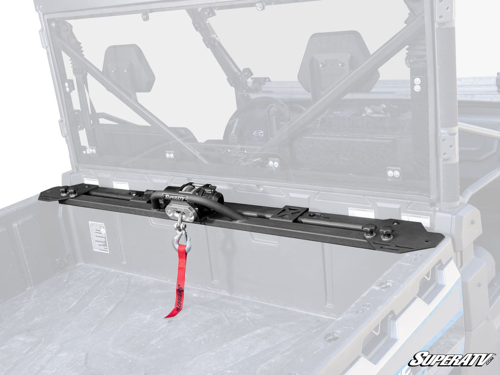 A CFMOTO UForce 1000 Bed Winch is mounted inside the black UTV cargo area, featuring a red strap on the winch hook. The UTV cab interior and roll cage are visible, with the SuperATV logo in the bottom right corner.