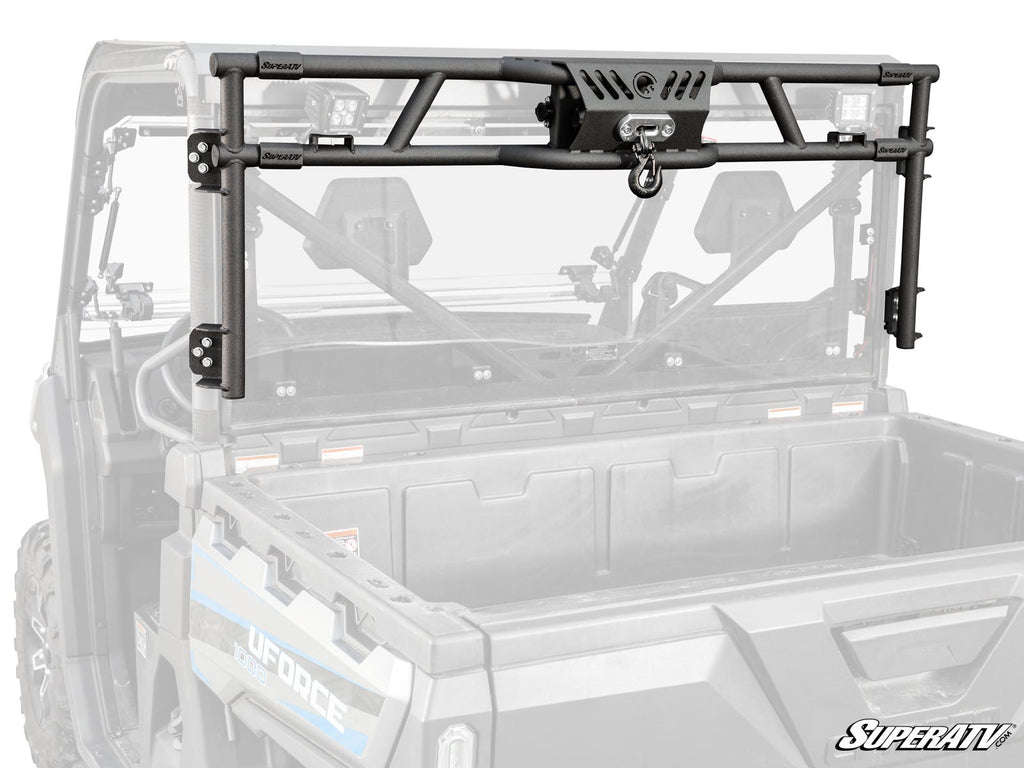A CFMOTO UForce 1000 Game Loader Rack, shown in black metal with mounting brackets and a centered winch, is installed on a utility side-by-side. The grayscale vehicle contrasts with the rack highlighted in color. SuperATV logo appears bottom right.