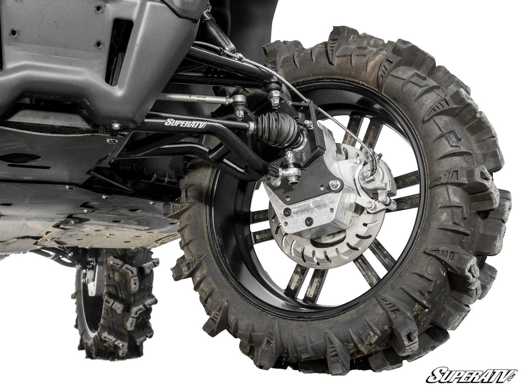 Close-up view of a CFMOTO UForce 1000 with 6 Portal Gear Lift, showcasing the rugged tire on a black rim, suspension arms, disc brake, and SuperATV logo. Another tire is visible in the background.