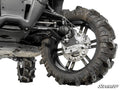 Close-up view of a CFMOTO UForce 1000 with 6 Portal Gear Lift, showcasing the rugged tire on a black rim, suspension arms, disc brake, and SuperATV logo. Another tire is visible in the background.