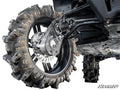 Close-up of a rugged ATV tire with deep treads on a heavy-duty black rim, showing suspension and brake components of a CFMOTO UForce 1000 with 8 Portal Gear Lift. The SuperATV logo appears in the lower right corner.