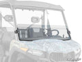 The CFMOTO UForce 600 Half Windshield is shown installed on a utility vehicle with a transparent, half-folded windshield, camo-patterned hood, side mirrors, visible front seats and steering wheel. SuperATV logo appears at the bottom right.