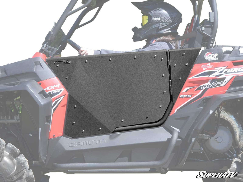 A person wearing a helmet and protective gear sits in a red and black off-road UTV featuring CFMOTO ZForce Aluminum Doors. The SuperATV logo is visible in the bottom right corner.