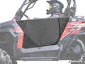 A person wearing a helmet and protective gear sits in a red and black off-road UTV featuring CFMOTO ZForce Aluminum Doors. The SuperATV logo is visible in the bottom right corner.