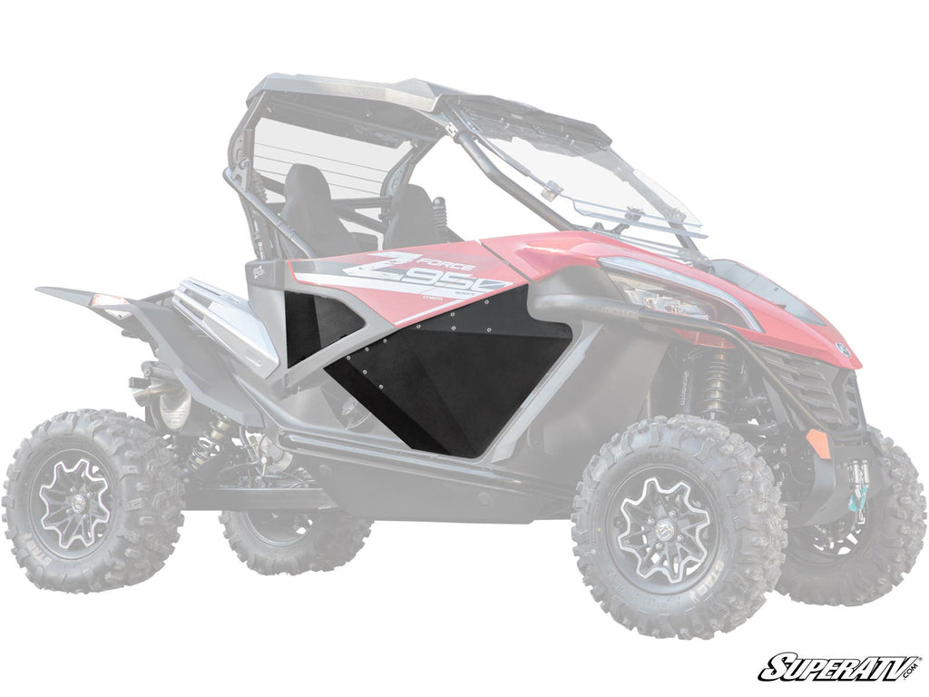The image features CFMOTO ZForce Aluminum Lower Doors installed on a red and black side-by-side. The rugged off-road vehicle has a roll cage, roof, chunky tires, and displays the “SuperATV” logo in the bottom right corner.