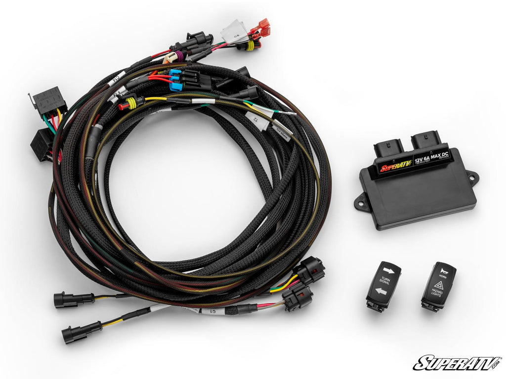 A CFMOTO ZForce 950 Deluxe Self-Canceling Turn Signal Kit is shown on a white surface, featuring a coiled cable bundle with connectors, a black SuperATV control unit, and two black electronic rocker switches with white icons and text.