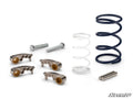 The image displays the Kawasaki Teryx KRX 1000 Rev1 Clutch Kit on a white background, featuring three curved metal pieces with gold bushings, blue and white coiled springs, two long bolts, three shorter bolts, and the SuperATV logo in the bottom right.