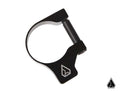 The Assault Industries M10 Accessory Clamp is a black metal clamp with a cylindrical hinge and a white geometric logo. Its displayed on a plain white background with a smaller version of the logo in the bottom right corner.