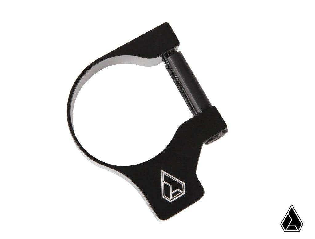 The Assault Industries M10 Accessory Clamp is a black metal clamp with a cylindrical hinge and a white geometric logo. Its displayed on a plain white background with a smaller version of the logo in the bottom right corner.