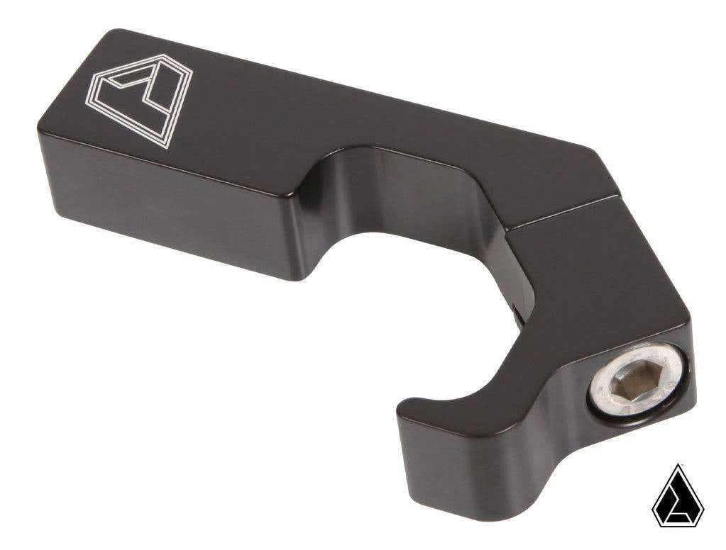 A black, angular metal Assault Industries M10 Pro-Fit Cage Clamp for Polaris and Can Am cages, featuring a geometric logo engraving on one end, a hex bolt on the other, and a curved inner section for mounting. A small logo appears bottom right.