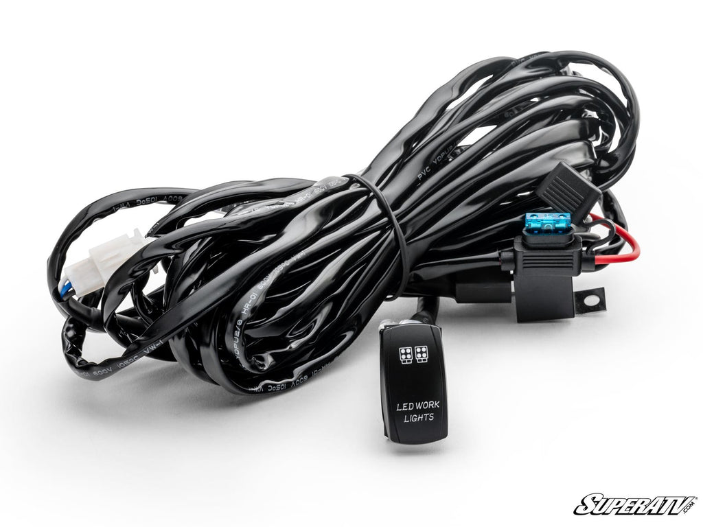 The LED Light Wiring Harness with Rocker Switch features a coiled black harness with connectors, a blue fuse, and a rocker switch labeled LED WORK LIGHTS with two LED symbols, shown on white background with the SuperATV logo.