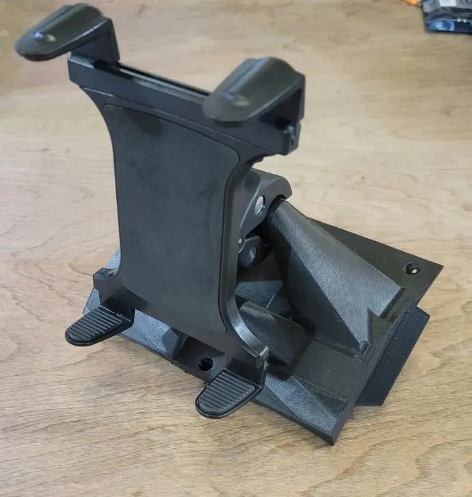 The Defender Limited & Cab Tablet/Phone Holder Center Insert, in black, features an adjustable angular base, two padded clamps for securing devices, and a design with sharp edges and screws for easy adjustment—perfect for any light wooden surface.