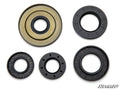 Five circular black rubber seals of varying sizes and designs, one with a gold metal ring, from the Can-Am Defender Front Differential Seal Kit are arranged on a white background. The SuperATV logo is visible in the lower right corner.