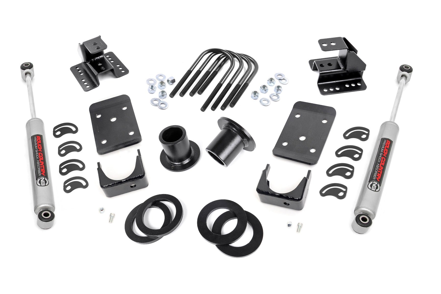 The Lowering Kit | Spr Drop | 1-2FR | 4RR for Chevy/GMC 1500 (07-13) is displayed on a white background, featuring two gray shocks, black brackets, U-bolts, spacers, washers, nuts, and curved mounting plates arranged symmetrically.