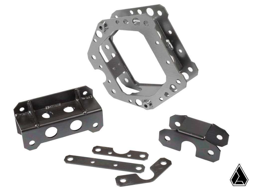 The Assault Industries F-22 Front Structural Reinforcement Kit (Fits: Maverick X3 XDS/XRS/XRC) is displayed with its metal bracket parts, featuring multiple holes and cutouts, neatly arranged on a white background with a small black logo in the corner.