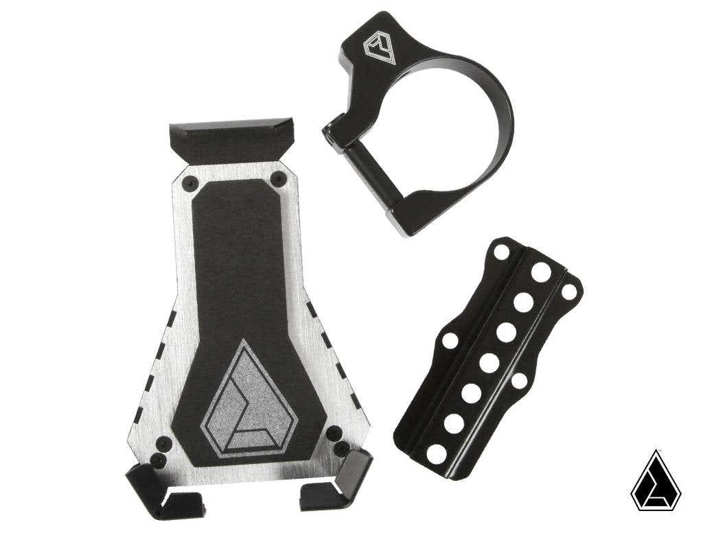 The Assault Industries Cell Phone Holder set includes a silver and black case with angled edges and logo, a black circular money clip, and a perforated black plate—displayed on white with a small triangular logo in the corner.
