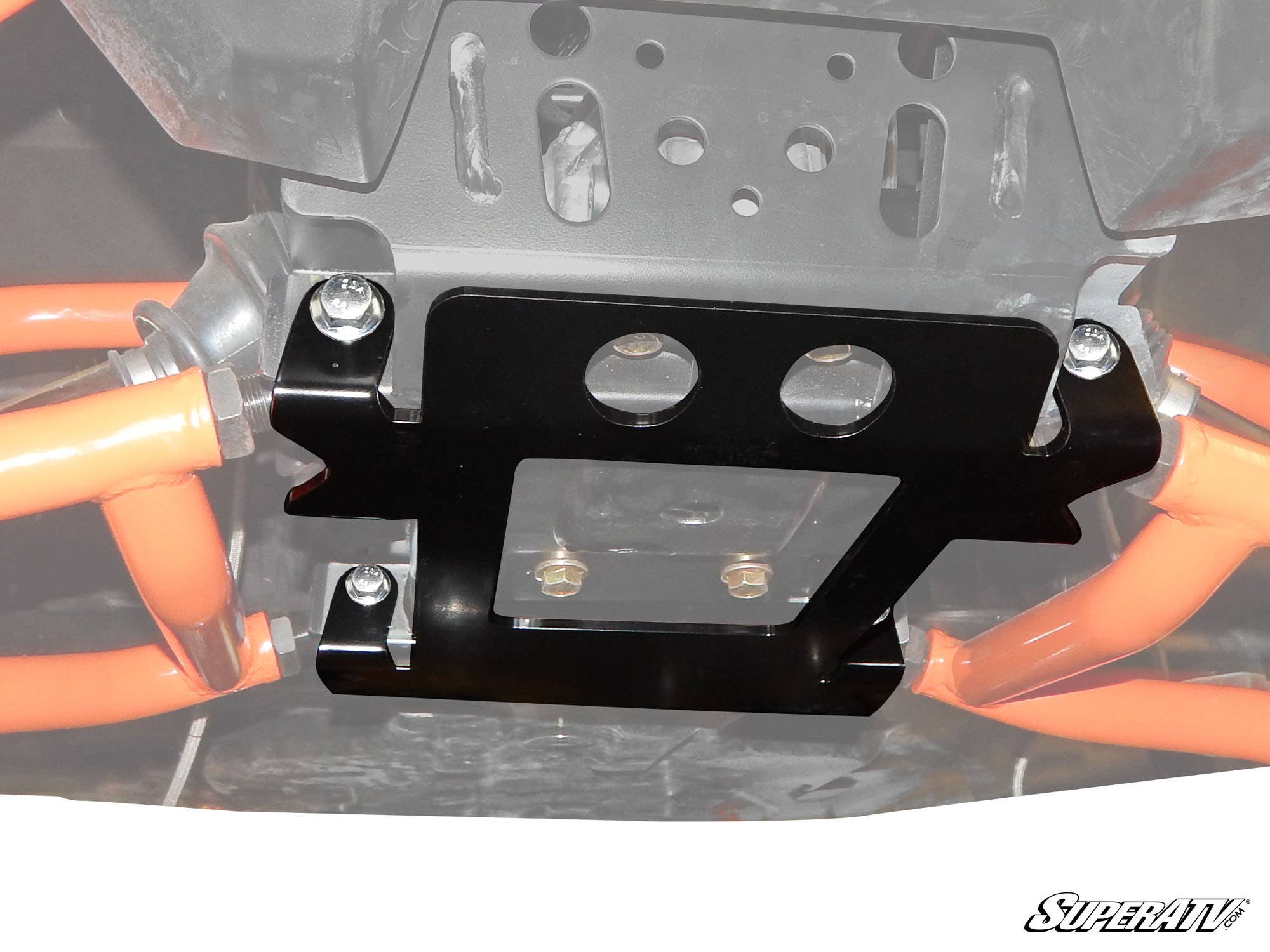 Close-up view of a Polaris General Frame Stiffener / Gusset Kit in black metal, mounted under a vehicle with silver bolts to orange suspension arms. The SuperATV logo is in the lower right, highlighting the protective and secure fit of this undercarriage 