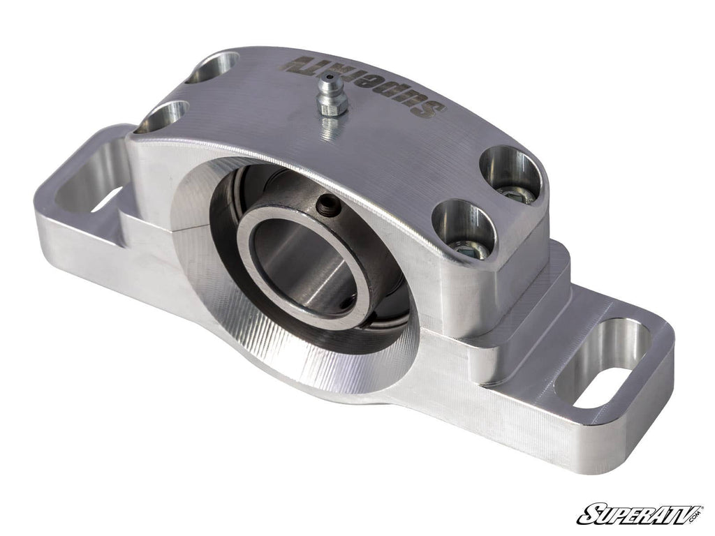 A Polaris General XP 1000 Heavy-Duty Carrier Bearing made of silver billet aluminum, featuring a central circular bearing, SUPERATV engraving on top, four hex bolts, mounting holes on each side, grease fitting above, and SuperATV logo on a white backgroun