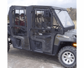 A Full Hard Cab Enclosure by Hard Cabs for 2009-14 Polaris Ranger XP 800 & 2014+ 570 Full Size Crew, featuring a black metal frame, clear doors, visible seats, and off-road capability, is parked outdoors.