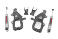 The Lowering Kit | 2 Inch FR & RR for Ford F-150 2WD (2004-2008) includes two black metal spindles, two Rough Country silver shock absorbers, and two small metal brackets, shown neatly arranged on a white background.