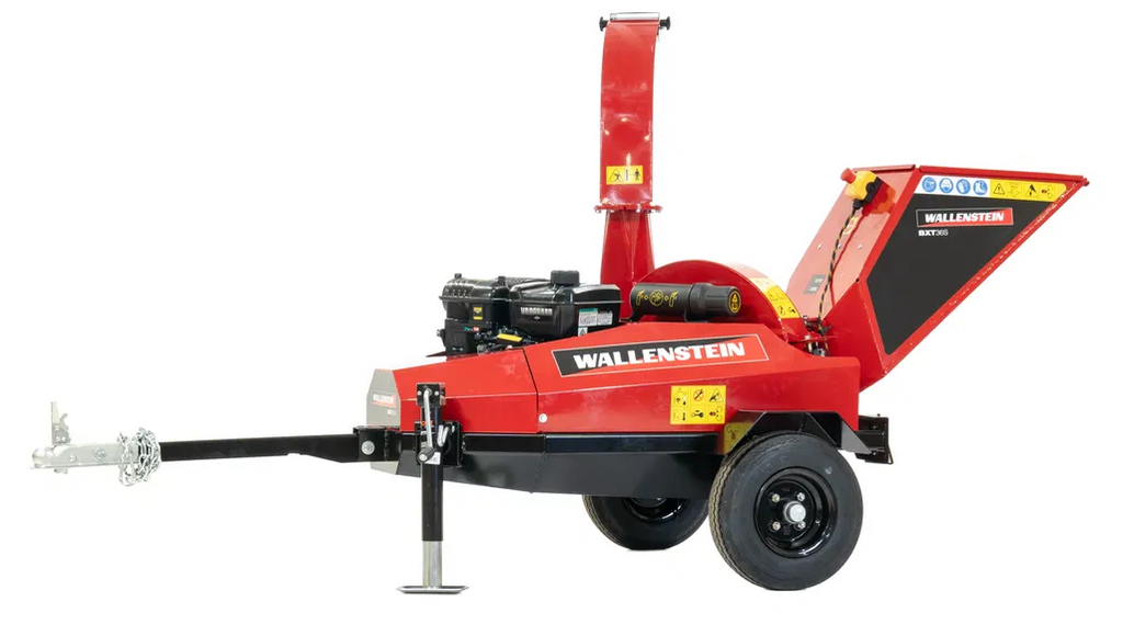 A red ATV/UTV Towable Wood Chipper with a black engine, large wheels, and metal tow bar features an open right-side intake chute and upright discharge chute. Yellow warning labels appear on several parts of the machine.