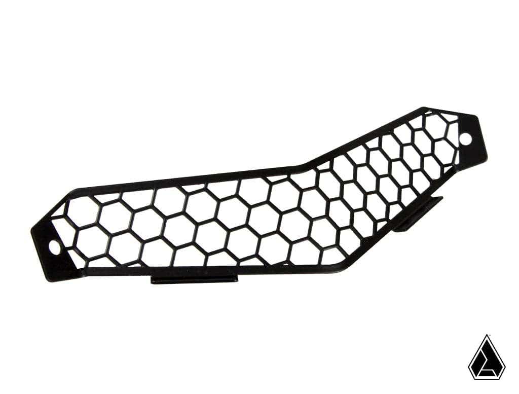 The Assault Industries Honeycomb Bonnet Grill for Canam Maverick X3 is a black plastic insert with a hexagonal pattern, two end mounting holes, and an angular bend. Shown on a white background with a small black geometric logo in the corner.