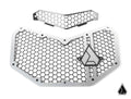 The Assault Industries Hellfire v2 Front Grill for Can-Am Maverick X3 features two metal mesh grilles with a hexagonal pattern and angular edges. The larger grille has a geometric triangular logo; the smaller is similarly designed above it.