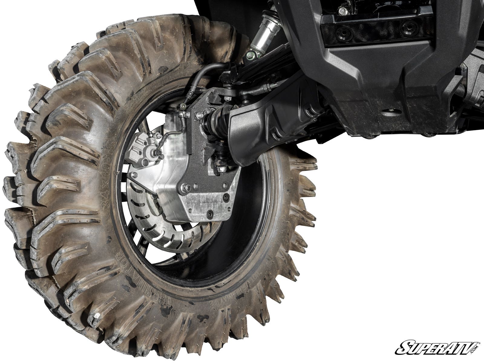 Close-up of a mud-covered, large off-road tire with deep treads mounted on a Honda Rancher 6 Portal Gear Lift. Visible are the metal wheel hub, suspension arms, and undercarriage skid plate. The SuperATV logo appears in the bottom right corner.