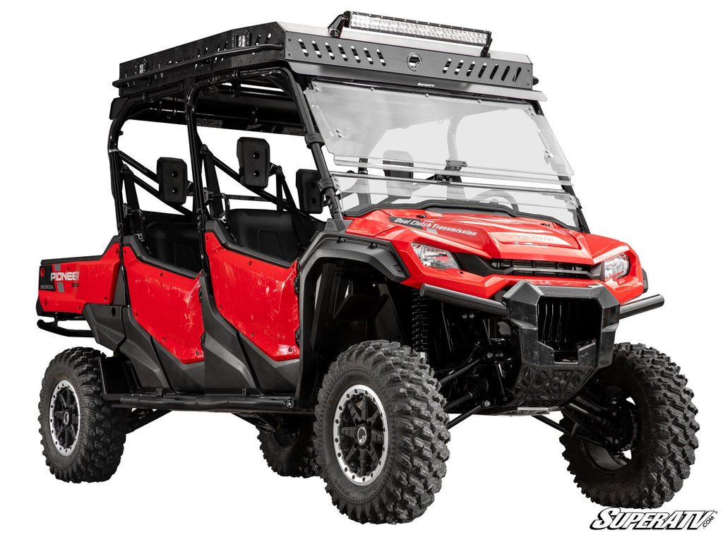 A Honda Pioneer 1000-6 equipped with a 3 Lift Kit, featuring rugged off-road tires, a roof rack with LED light bar, clear windshield, open half doors, black accents, and Pioneer 1000 branding on the side.