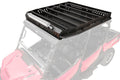 The Honda Pioneer 1000-6 Outfitter Roof Rack, featuring black metal construction with slotted rails, side walls, and a front light bar, is shown mounted atop a red off-road utility vehicle with a semi-transparent body to highlight the rack.