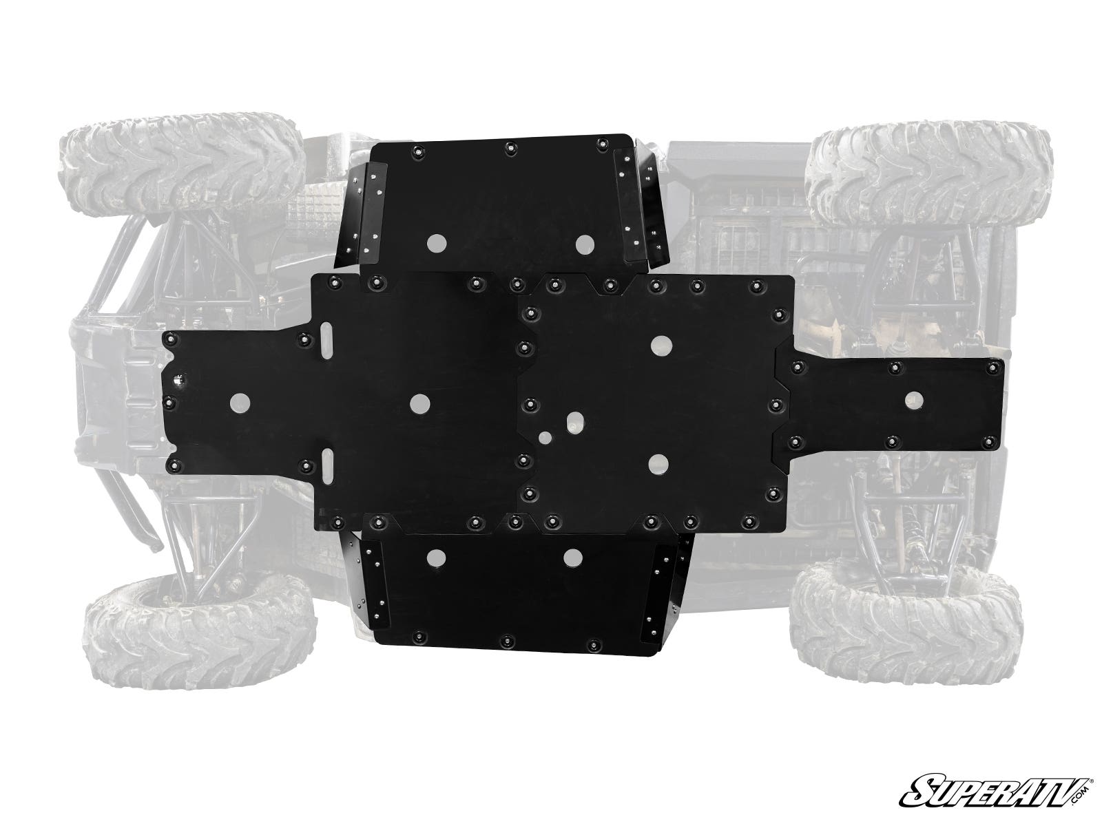 The Honda Pioneer 700 Full Skid Plate, made of black metal, is mounted to the underside of an off-road vehicle. The vehicle and large tires are faintly visible in the background, with the SuperATV logo displayed in the bottom right corner.