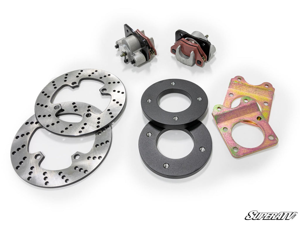 The Honda Rubicon Front Disc Brake Kit includes two perforated rotors, two calipers, two black spacers, and two gold mounting plates. Shown on a white background with the SuperATV logo in the bottom right corner.
