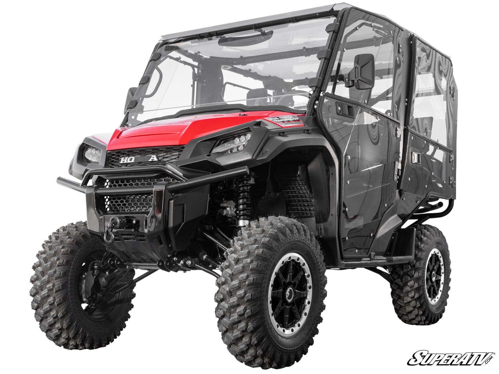 A rugged Honda Pioneer 1000 featuring a 3 Lift Kit, red and black design, large knobby tires, clear enclosed cab, sturdy front bumper, angular headlights, and the SuperATV logo in the lower right corner on a white background.