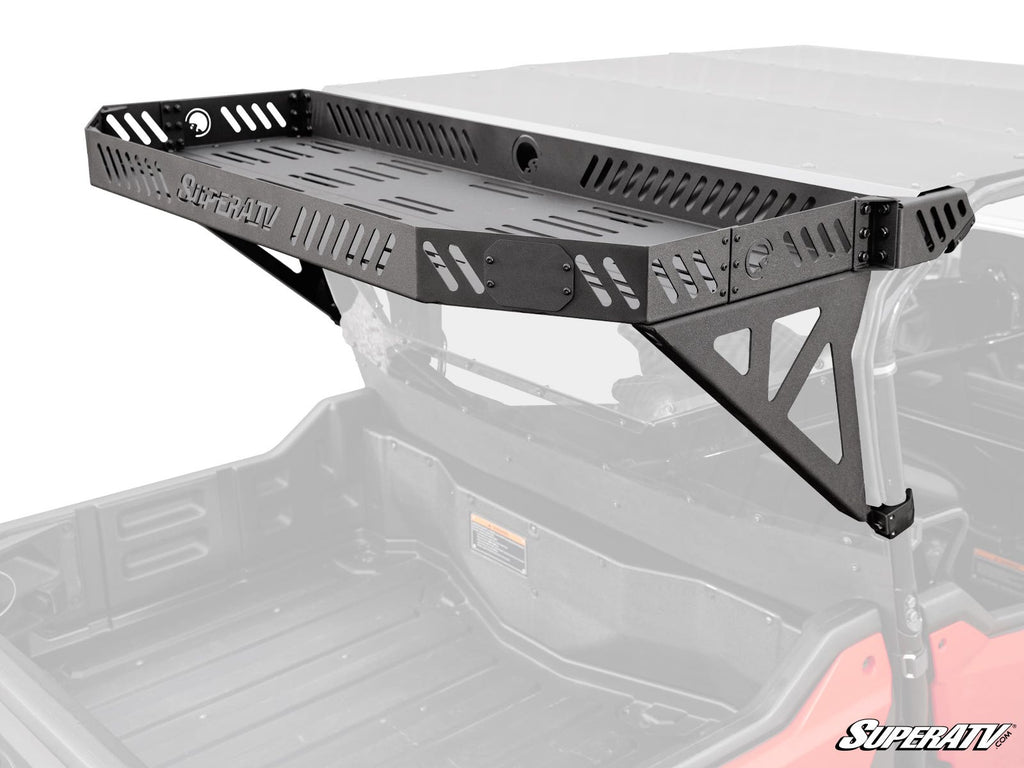 A black metal Honda Pioneer 1000-6 Bed Rack Echo with perforated sides and bottom is mounted above the cargo bed of a red off-road vehicle, secured with triangular brackets and featuring the “SuperATV” logo on the front panel.