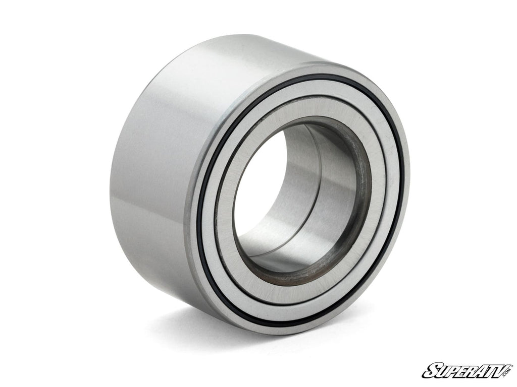 A close-up of the Up & Running Honda Talon Wheel Bearing Replacement, featuring a shiny, silver cylindrical shape with concentric rings, resting on a white surface with the SuperATV logo in the bottom right corner.