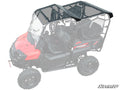 A Honda Pioneer 700-4 with a black tinted roof is shown, covering both front and rear seats. Mesh side nets are visible. Only the SuperATV roof and vehicle front are in full color; the rest is faded, with the SuperATV logo in the corner.