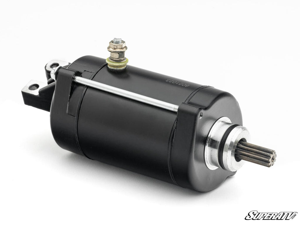 The Up & Running Honda Big Red Starter is a black cylindrical electric starter motor with a silver gear shaft and mounting bracket, shown angled on a white background. The SuperATV logo appears in the lower right corner.