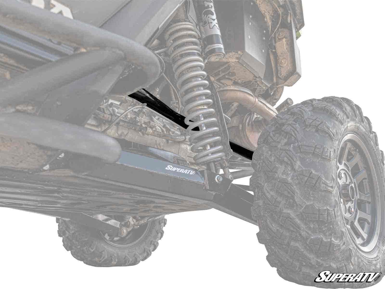 Low-angle view of a Honda Talon 1000R’s rear suspension highlights the coil spring, shock absorber, and durable Honda Talon 1000R Rear A-arms. The lifted setup with large, rugged tire is built for rough terrain. Faded, high-contrast image effect.