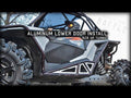 A person wearing goggles sits in a rugged black and gray RZR XP Turbo with large knobby tires. The image highlights the installation of Polaris RZR XP Turbo Lower Doors. Bold text reads: ALUMINUM LOWER DOOR INSTALL RZR XP TURBO.