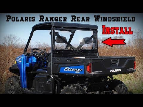 A blue Polaris Ranger XP utility vehicle is parked in a grassy field. Large text reads Polaris Ranger XP 1000 Rear Windshield Install, with an arrow pointing to the rear windshield on the vehicle.