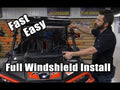 A man installs a Polaris Ranger XP 900 Full Windshield on a black and orange off-road vehicle in a workshop. Bold text reads, “Fast Easy Full Windshield Install.” Tools and parts hang on the wooden wall behind him.