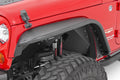 Close-up of a Jeep Wrangler JK (2007-2018) front left fender with a Rough Country Steel Fender Flare, large off-road tire, exposed suspension coil and shock absorber. “Sahara” and “Wrangler Unlimited” badges appear on the side.
