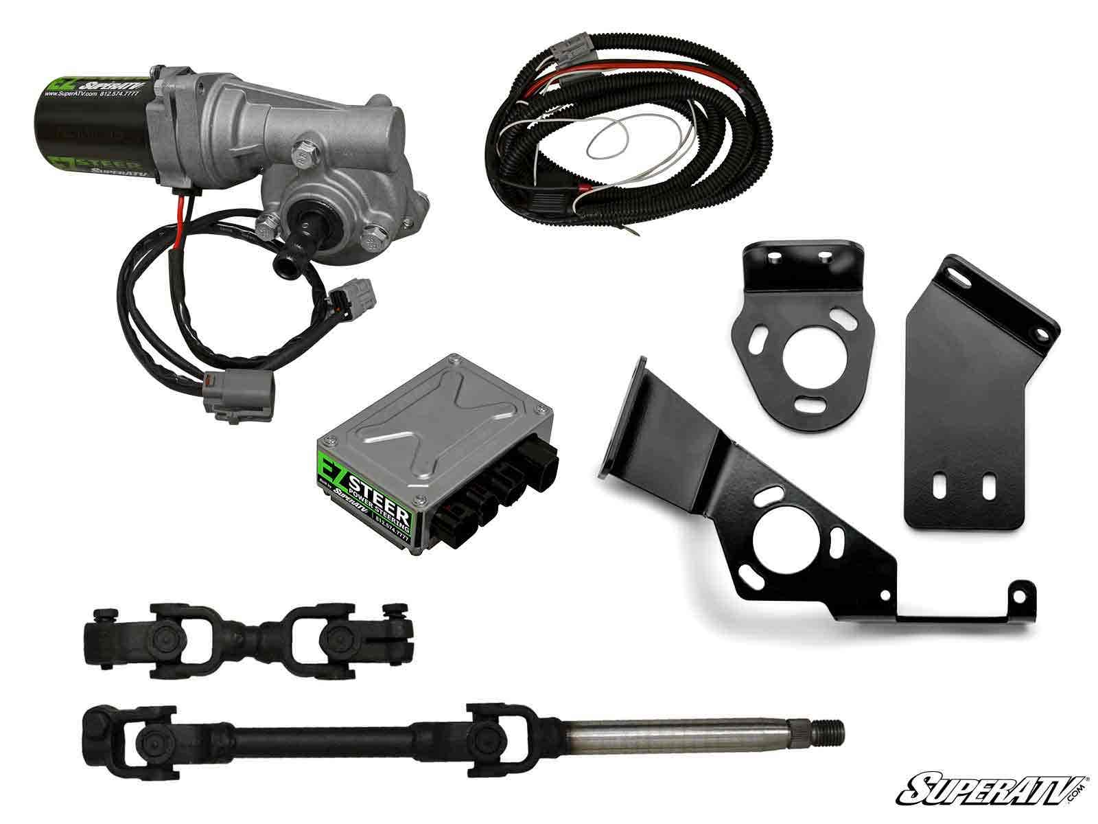 The John Deere Gator 835M Power Steering Kit is shown with a motor, wiring harness, control unit, steel brackets, shaft, and two U-joint couplers on a white background. The SuperATV logo appears in the lower right corner.