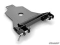 The Kawasaki Mule Pro Plow Pro Snow Plow Mount is a black, glossy metal hitch plate with a central hole, angled edges, and two curved pins with cotter pins on each side. The SuperATV logo is at the bottom right, set against a plain white background.