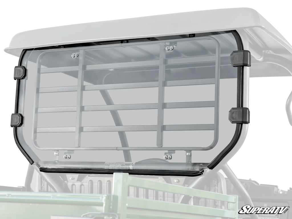 A clear, rectangular polycarbonate Kawasaki Mule SX Rear Windshield with black mounting clamps is attached to the back of an off-road UTV. The SuperATV logo is visible in the bottom right corner of the panel.