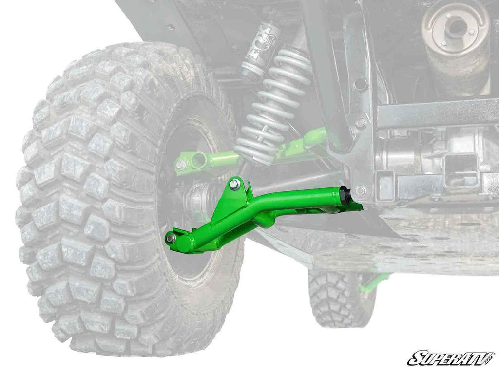 A vivid green Kawasaki Teryx S Atlas Pro Rear A-Arm stands out on an off-road vehicle’s rear wheel, while the tire, coil spring, and frame are faded gray. The SuperATV logo appears in the bottom right corner.