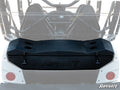 A Kawasaki Teryx 4 Cargo Box in black is mounted to the rear of a white off-road UTV. The box features four cup holders on top, side latches, and displays the SuperATV logo. The image shows the UTV’s roll cage and seats.